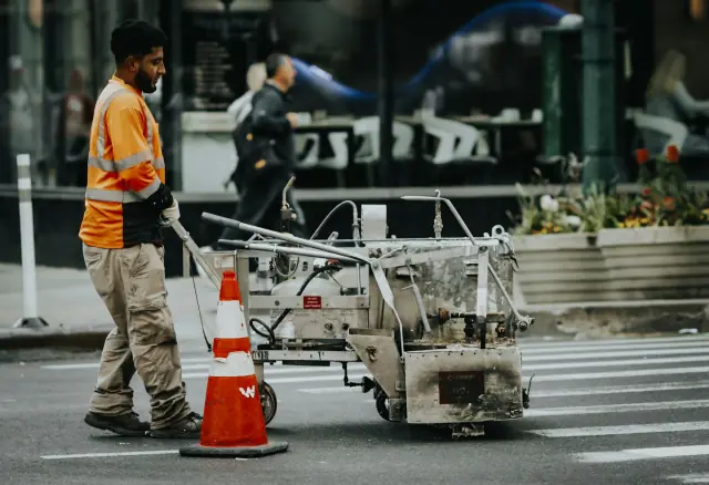 Worker operating line-marking equipment on pavement